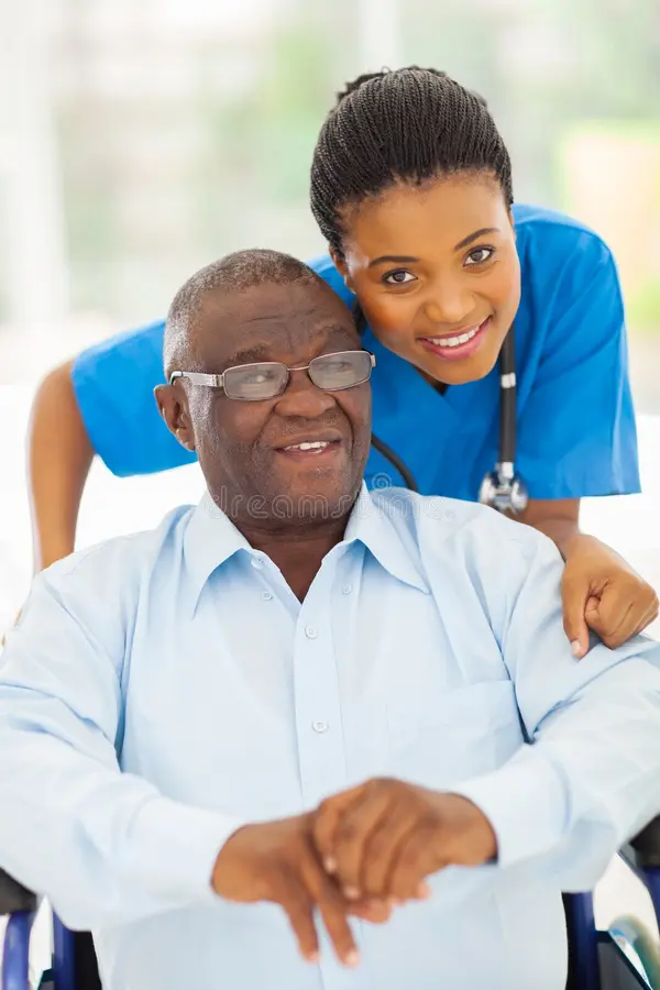 A smiling caregiver leaning beside an older man in a wheelchair